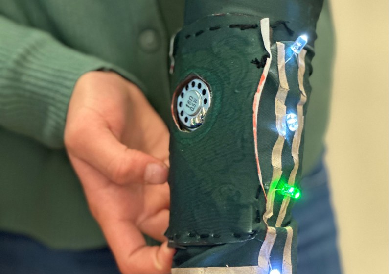 A student-built wearable cuff with wired LEDs and a sensor, worn on the forearm
