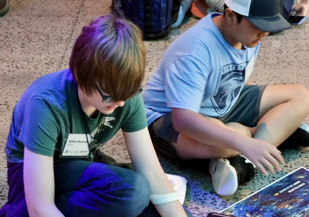 Students working across a printed sustainable-city map during a systems challenge